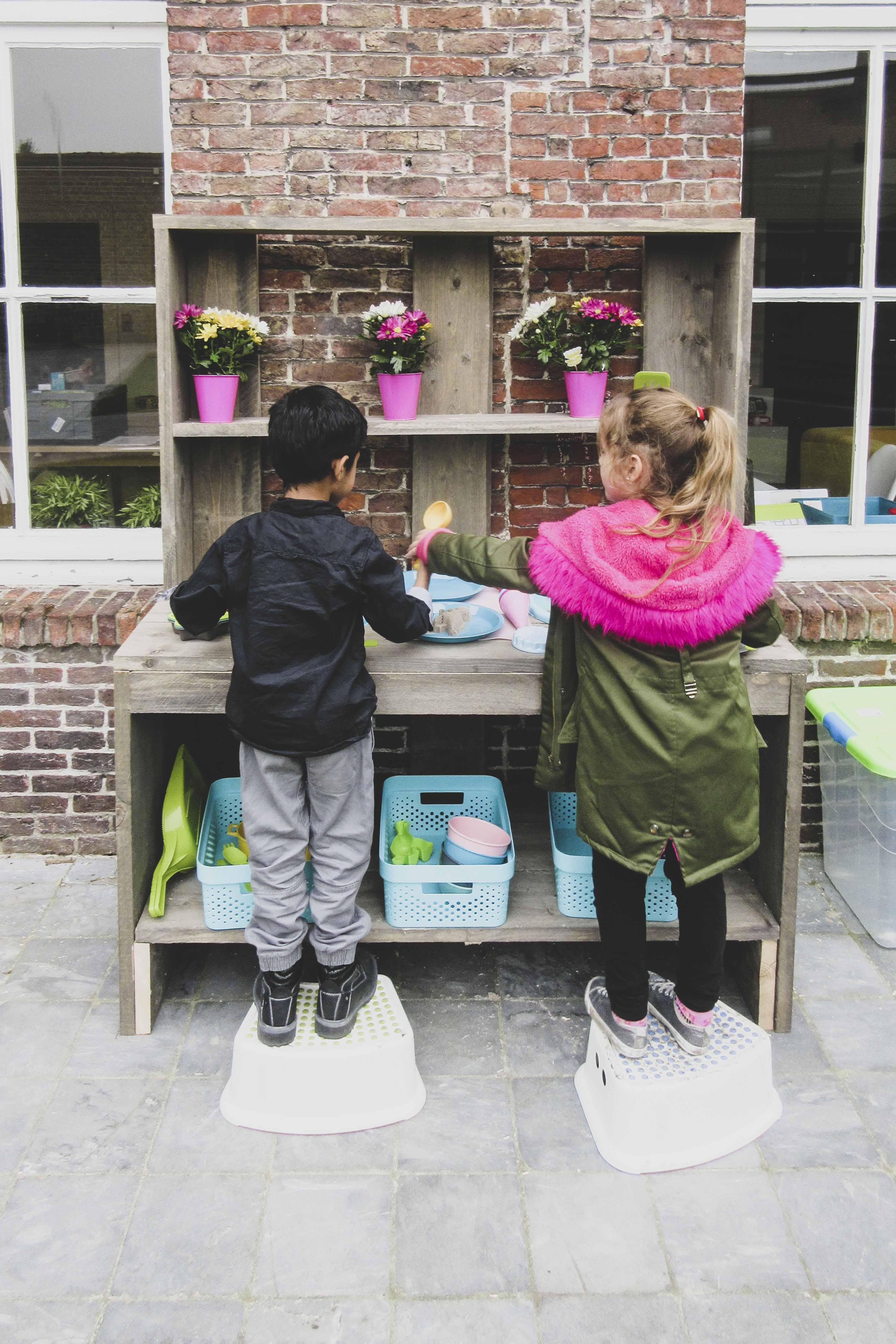 Kindjes spelen met zand Twee kindjes die samen met zand aan het spelen zijn.